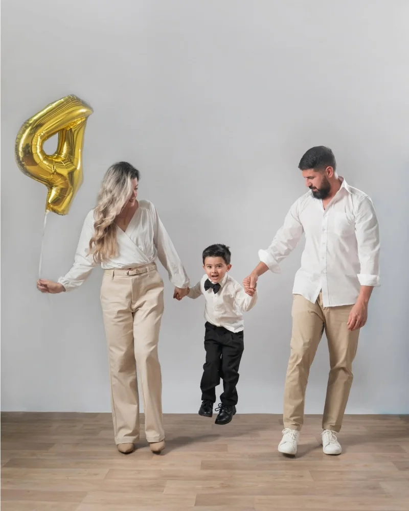 Familia caminando de la mano en el estudio con un globo del número cuatro